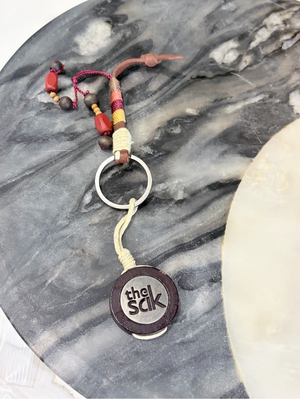 The Sak Brown Leather Logo Keyring with Red Beaded Tassel